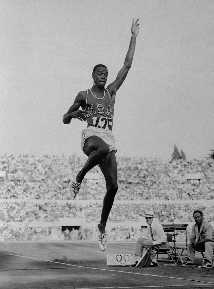 Ralph Boston in mid-air during the long jump at the 1960 Rome Olympics, U.S.A. across his chest