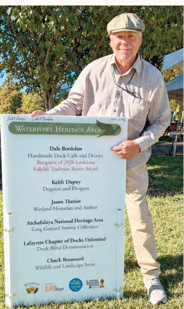 Dale Bordelon holds the Waterfowl Heritage Area sign at Festivals Acadiens et Créoles in Lafayette.