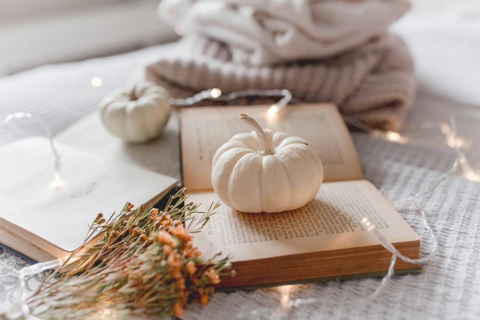 white autumn aesthetic. folded sweaters, tiny white pumpkins, old books, fairy lights and dried flowers