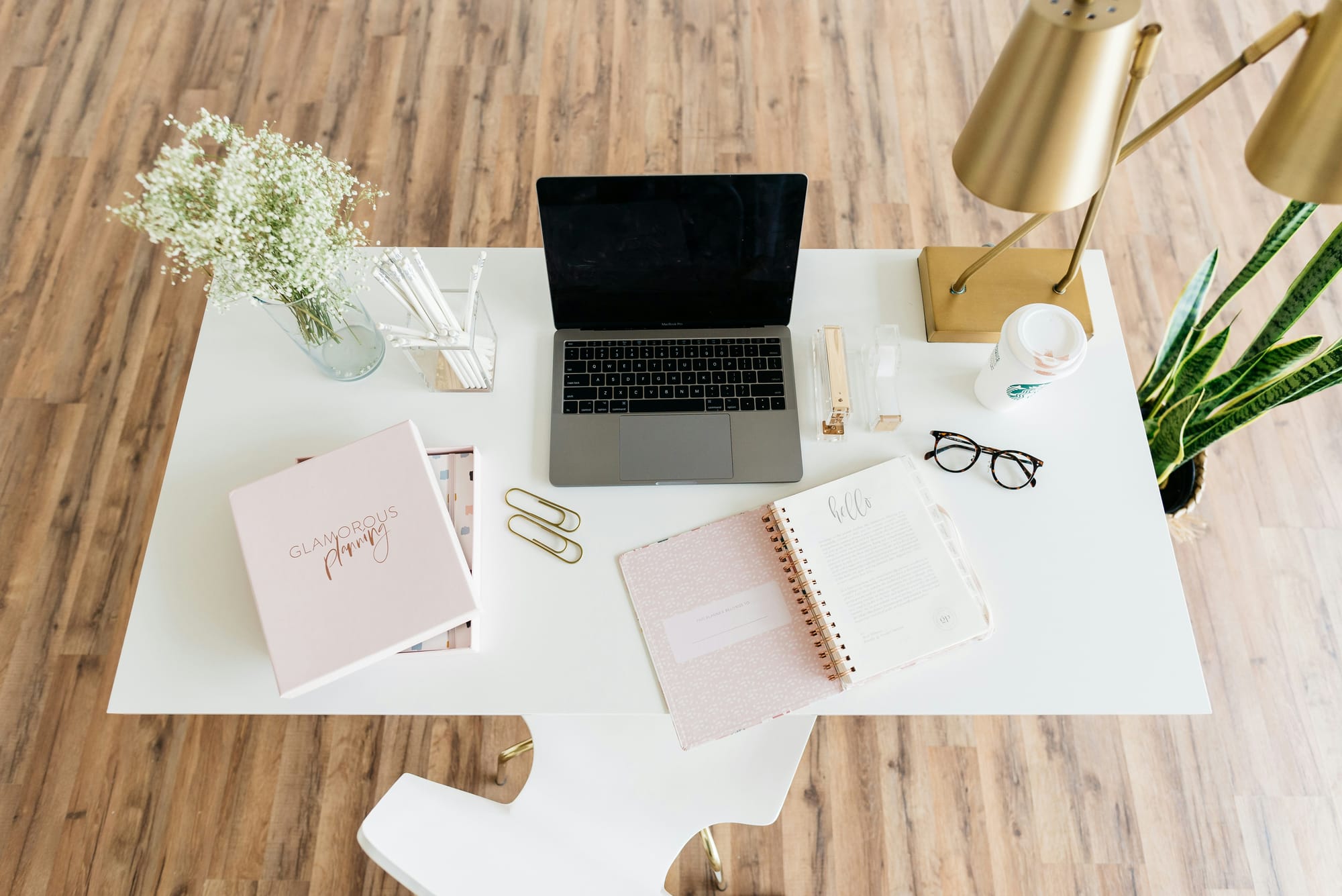 Minimalist white desk with laptop and soft gold accents — a calm space for functional medicine consultations and personalized healing plans.