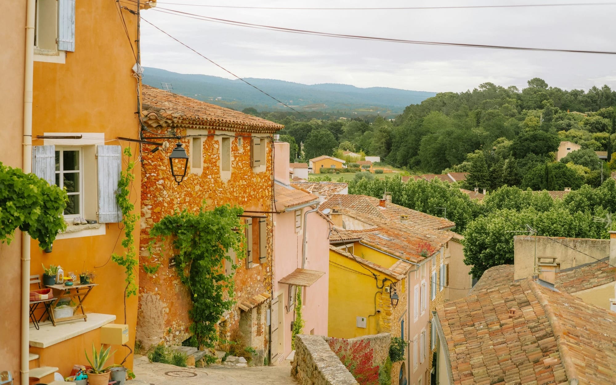 Mediterranean hillside village with warm‑toned houses, climbing greenery, and walkable paths — illustrating how built environments naturally support connection and longevity, central to Blue Zones principles.