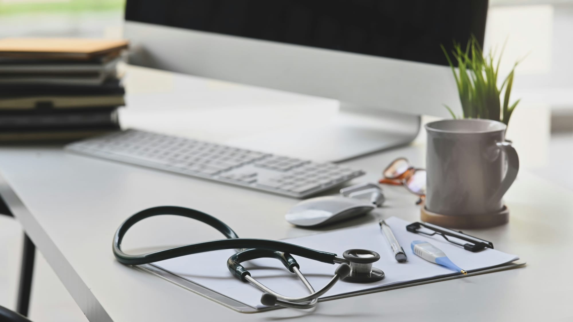 Clean medical desk setup featuring a stethoscope, clipboard, and computer, representing professional functional medicine consultations and clinical guidance.