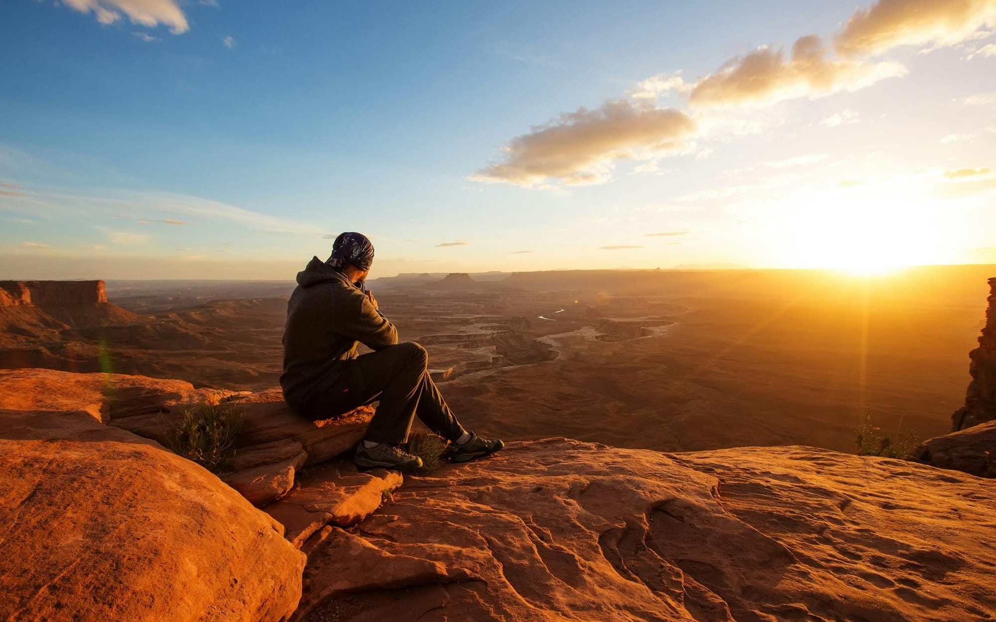Person sitting on canyon edge at sunset, symbolising reflection and the physiological imbalance of HPA axis dysregulation.
