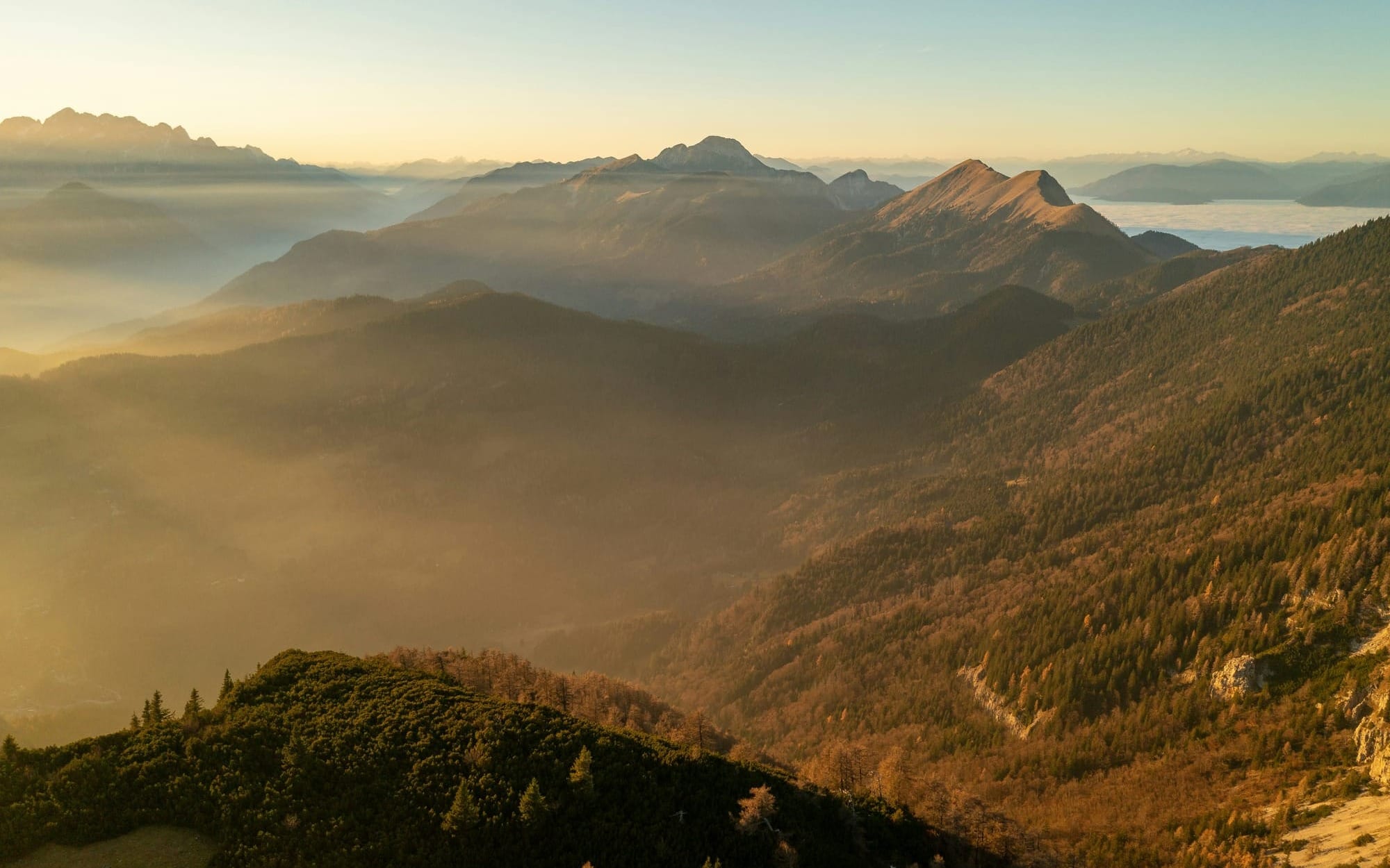 A wide, scenic landscape photograph of mountain ridges layered behind soft morning mist, bathed in warm golden sunlight at sunrise, serving as an encouraging metaphor for the step-by-step journey of chronic illness recovery.