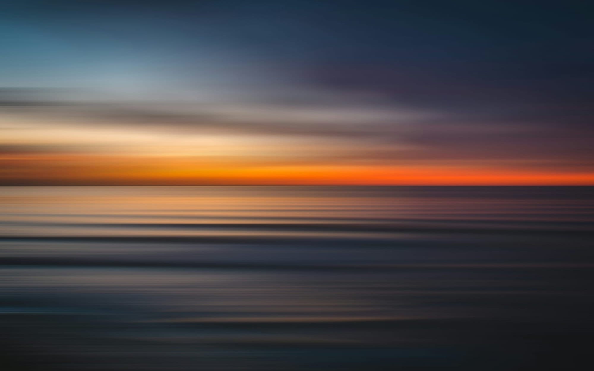A conceptual horizontal motion-blur photograph of a calm seascape at dawn, featuring deep indigo and blue tones transitioning into a radiant amber horizon, symbolically representing the forward-looking roadmap and bright future of global neurological medicine.