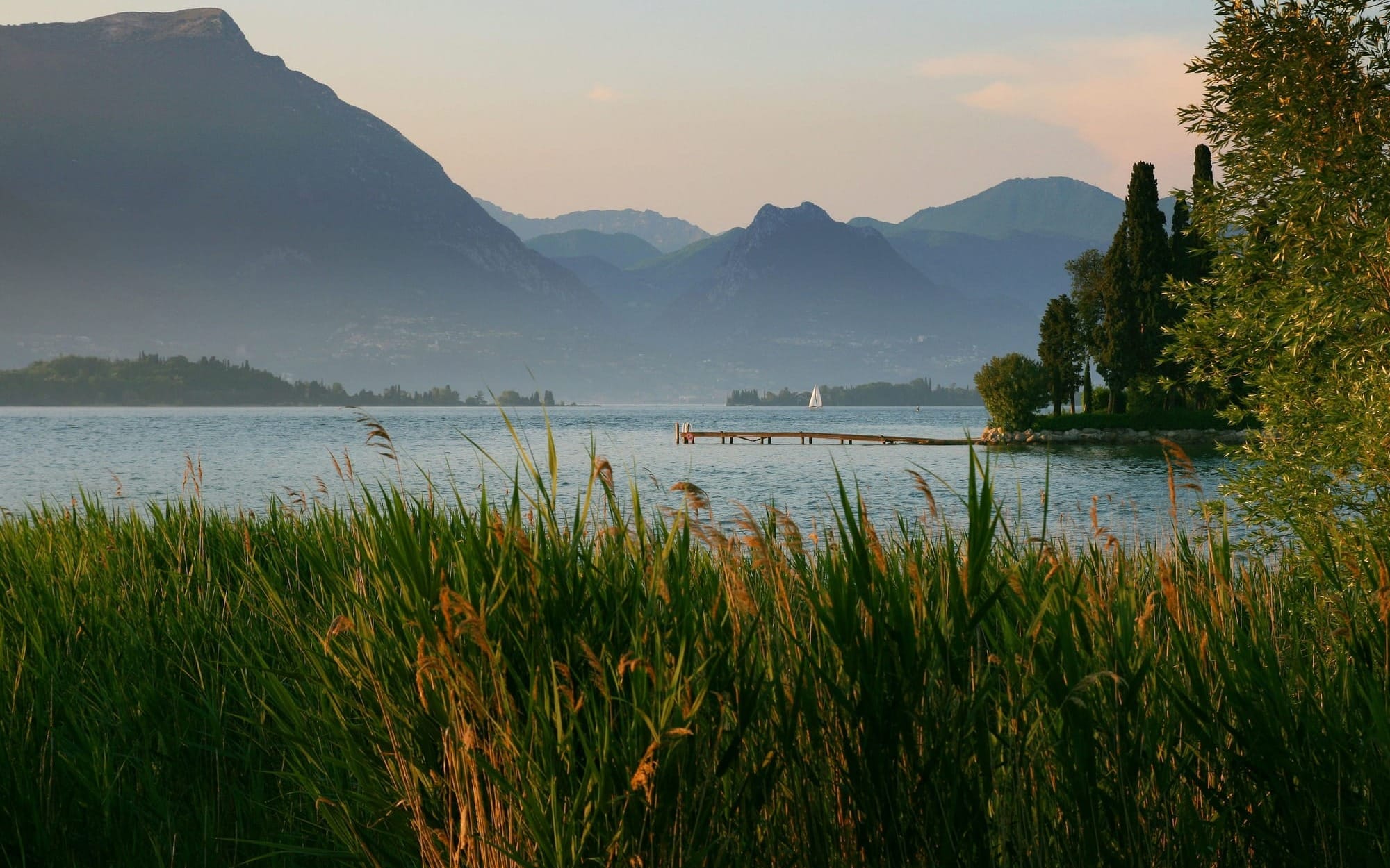 A serene, wide landscape showing a calm, mirror-like lake reflecting snow-capped mountains with a peaceful wooden dock extending into the still water, serving as a visual metaphor for mental clarity and cognitive longevity.