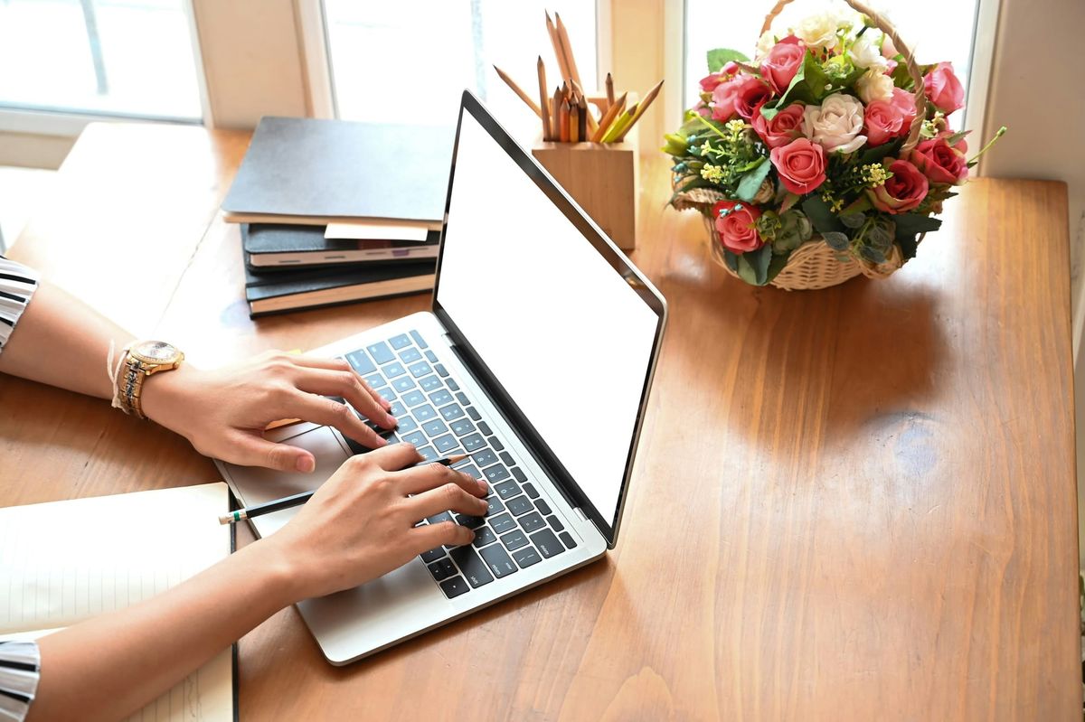 Bright, modern workspace with a computer, open notebook, and fresh flowers, symbolizing a welcoming environment for functional medicine, health coaching and wellness programs.
