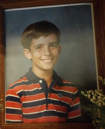 A boy who looks around 10-years-old, wearing a blue and red striped Polo shirt from the early 1980s.