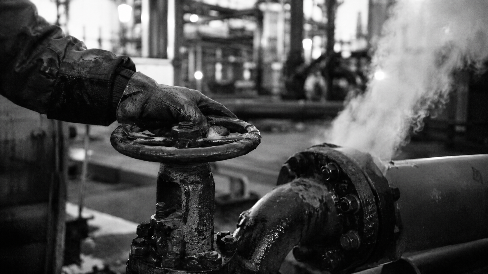 Oil pipeline valve worker gloved hand