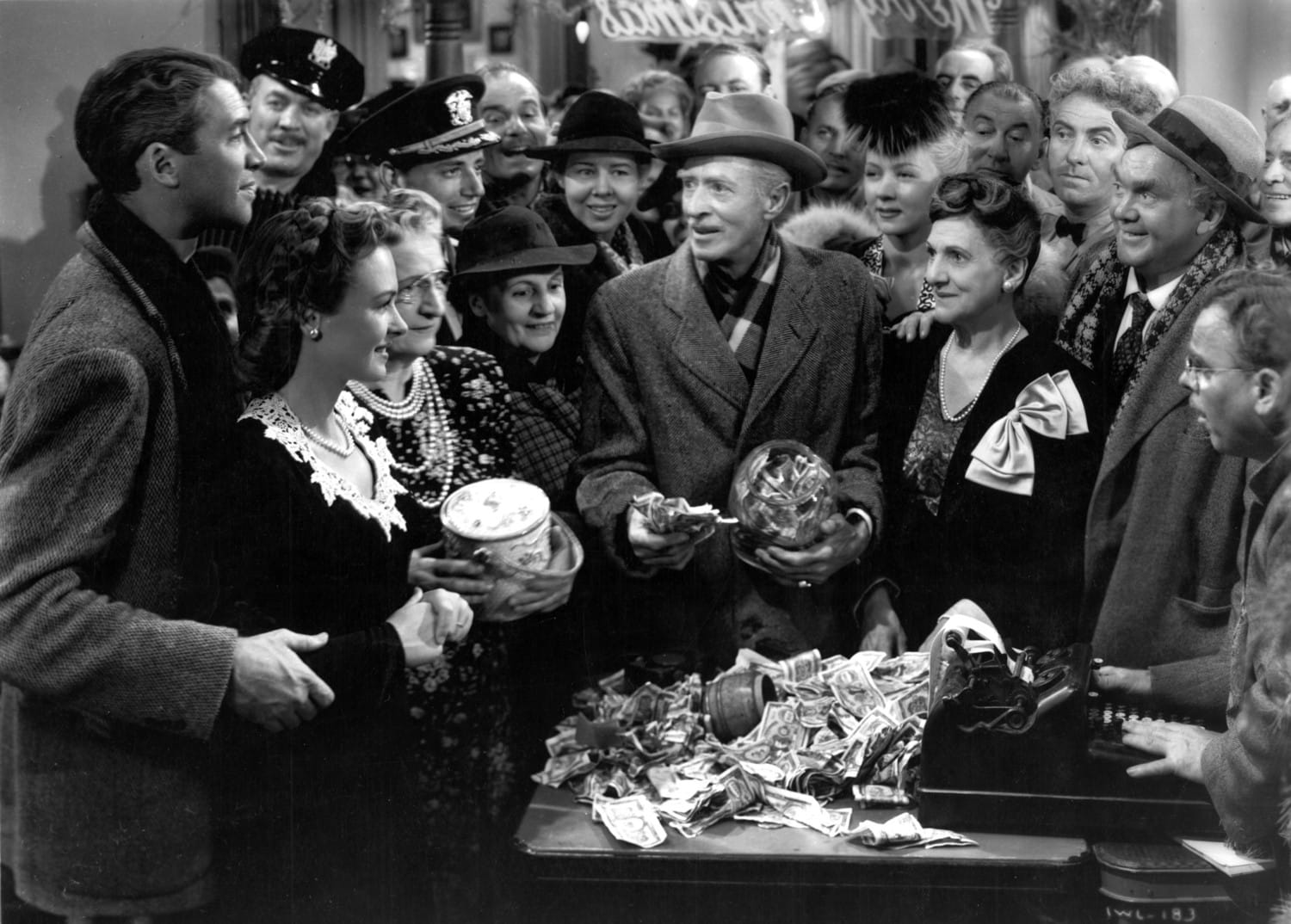 George and Mary look on as their fellow townspeople give them the money that will help keep George out of jail. 