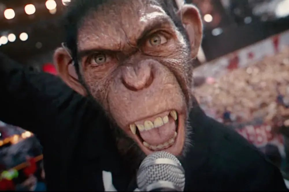 A humanoid chimpanzee clutching a microphone sneers at the camera in extreme close-up.
