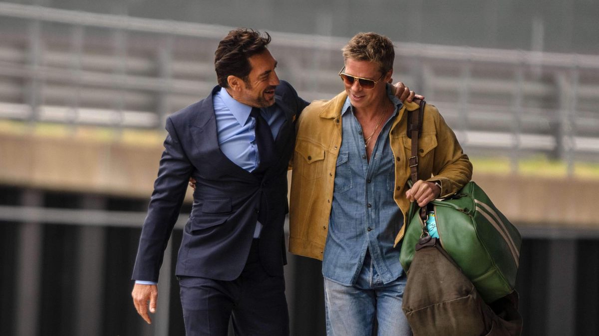 Javier Bardem and Brad Pitt walk along together, all chummy. Javier is in a suit; Brad in a shirt and jeans.