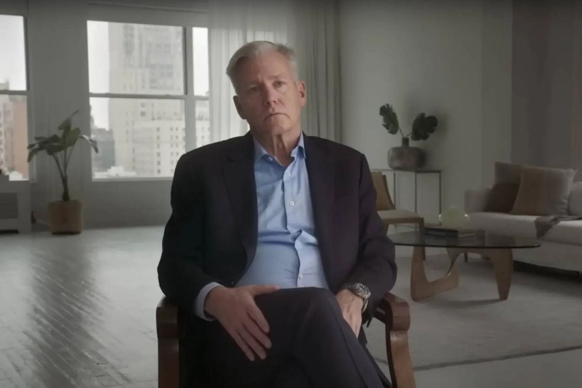 Journalist Chris Hansen, in a suit, sits down for a talking-head interview in a completely beige studio space.