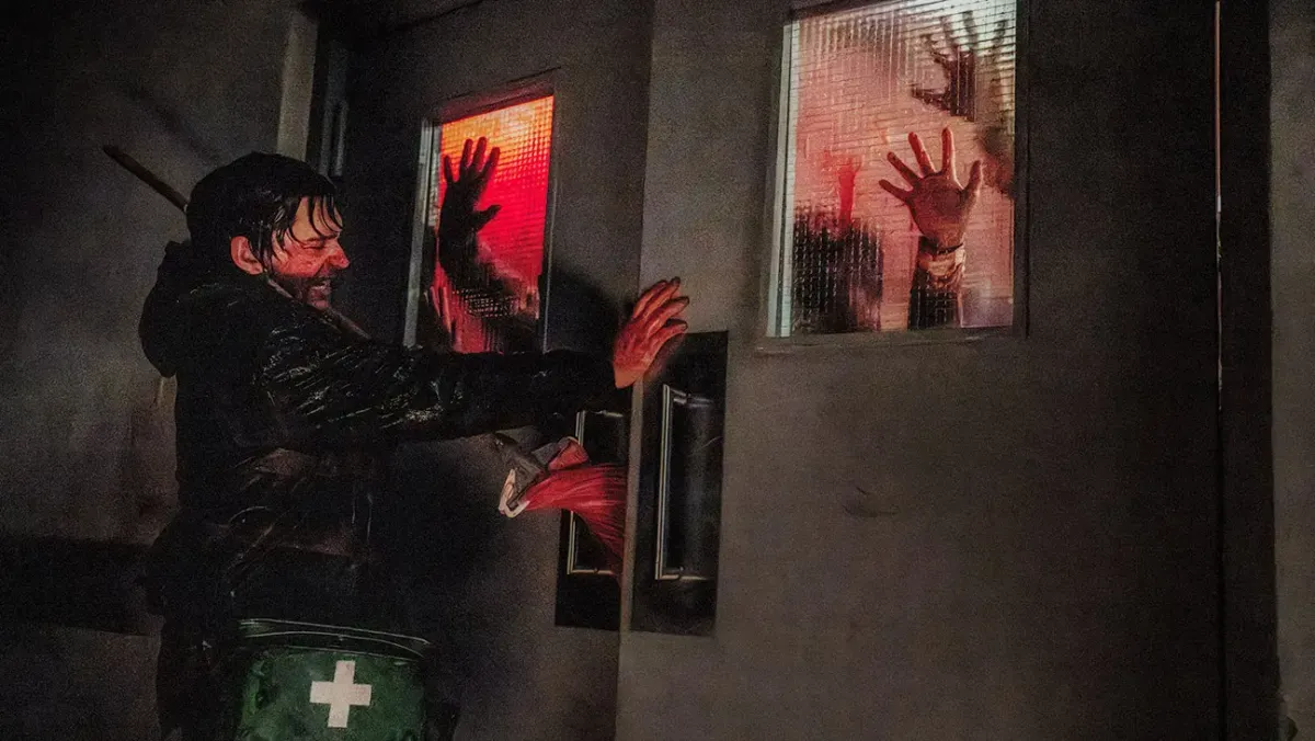 Austin Abrams desperately closes a set of double doors on a horde of zombies in Resident Evil.