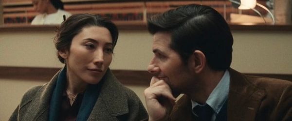 Gemma and Mark sit in a room, looking at each other with wistful sadness. She's got a great grey coat.