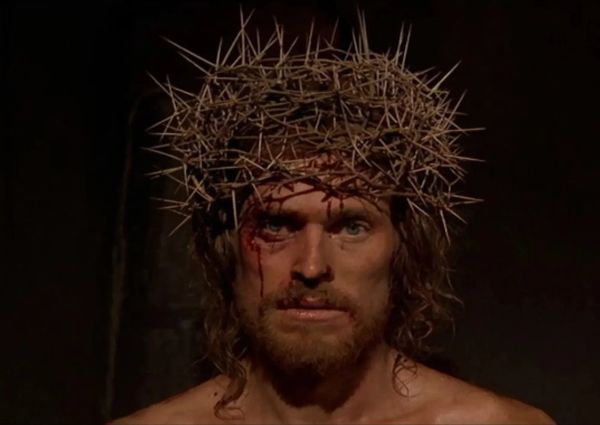 Jesus stares at the camera, wearing a crown of thorns. Blood trickles down his face.