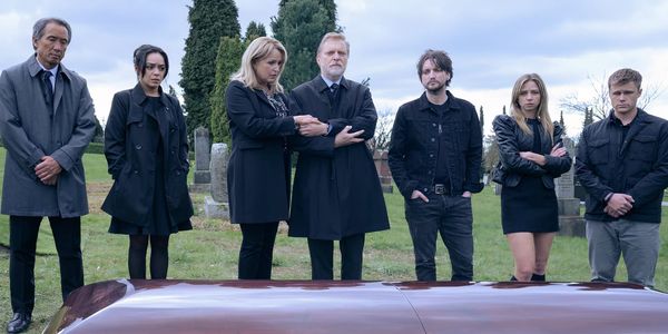 The characters of Final Destination: Bloodlines stand in a cemetery. They are dressed in black and overlook a casket.