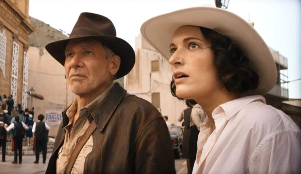 Indiana Jones -- in trademark fedora -- and his compatriot Helena Shaw, a pale woman with brown hair and eyes, stare at something.