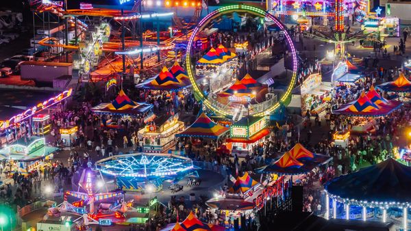 The midway at the Minnesota State Fair is full of rides and games, all glowing neon-bright in the night.