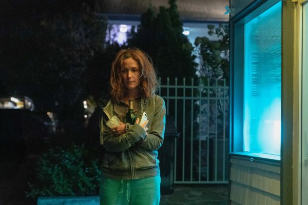 Rose Byrne, hair straggly and face glum, stands outside a hotel, clutching a bottle of wine and a baby monitor.