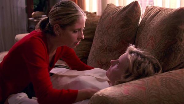 Buffy, in a red sweater, crouches over the prone corpse of her mother, Joyce, who is very obviously dead.