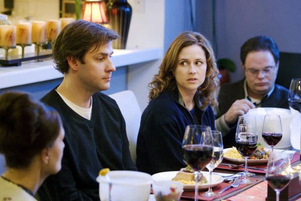 Jim and Pam sit at the table for an awful dinner party. Dwight is poking at something in the background.