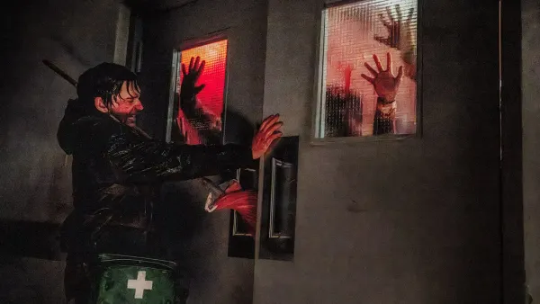 Austin Abrams desperately closes a set of double doors on a horde of zombies in Resident Evil.