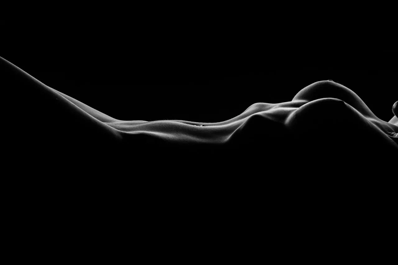 Artistic black and white bodyscape showing water beads glistening on oiled skin