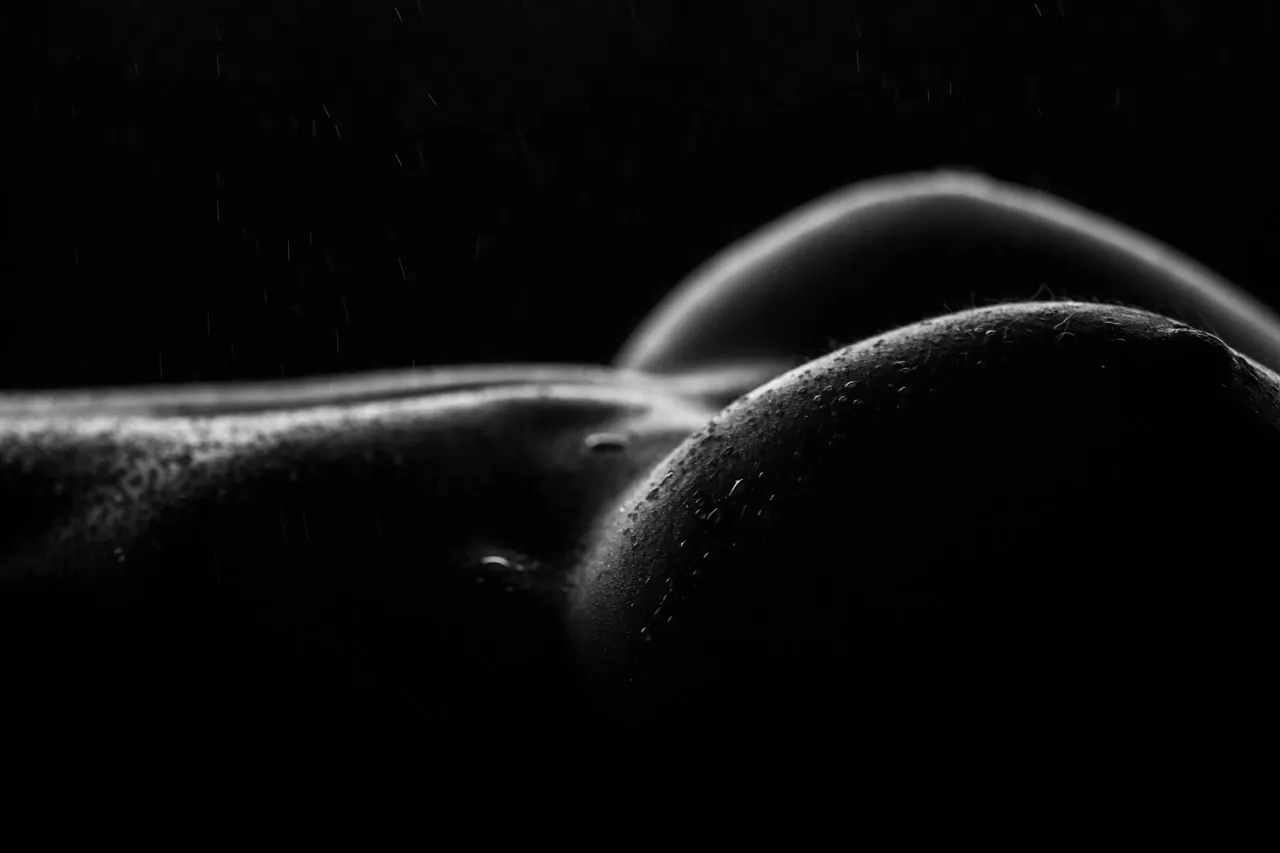 Close-up bodyscape with wet look droplets highlighting curves in fine art nude photography