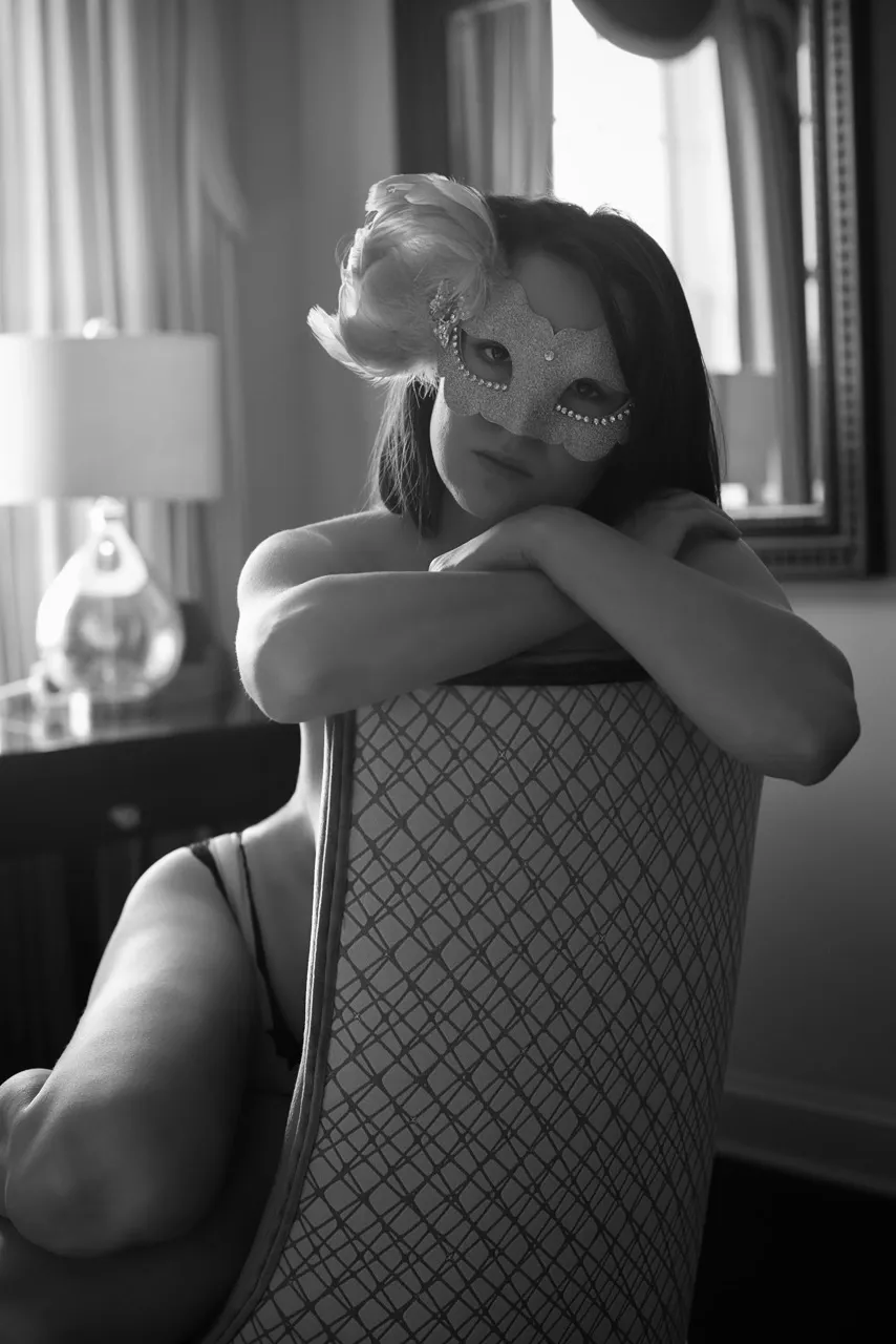 Luxury boudoir photo with masked model in unfamiliar hotel room