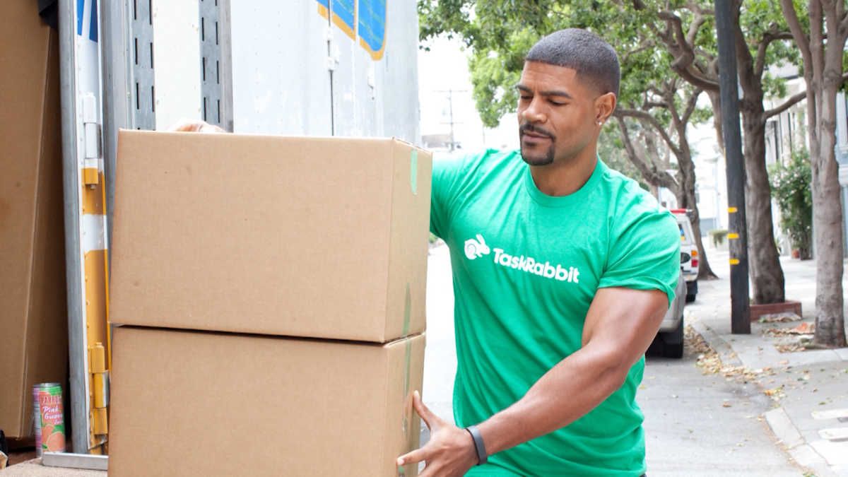 Taskrabbit tasker worker wearing a green taskrabbit tshirt loading boxes into a van