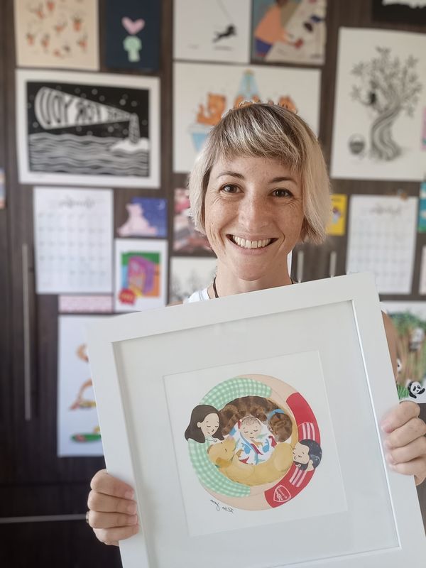 Illustrator and paper artist Rita Jane holding one of her signature Group Hug artworks