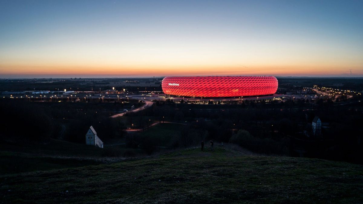 Die rot beleuchtete Allianz Arena in München in der Abenddämmerung