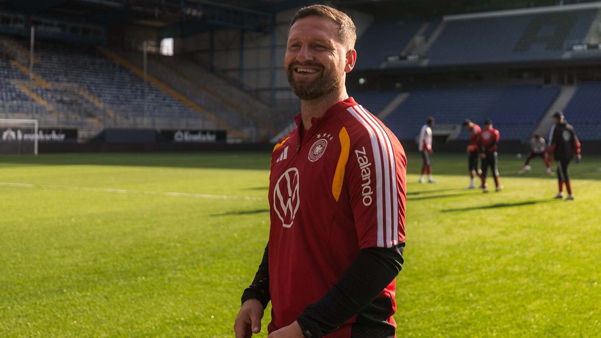 Shkodran Mustafi lacht im Trainingsanzug der Nationalmannschaft auf dem Rasen