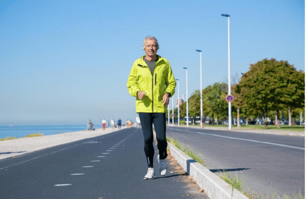 happy-excited-mature-man-wireless-headphones-jogging-along-river-bank-outside-senior-jogger-training-marathon-front-view-activity-age-concept