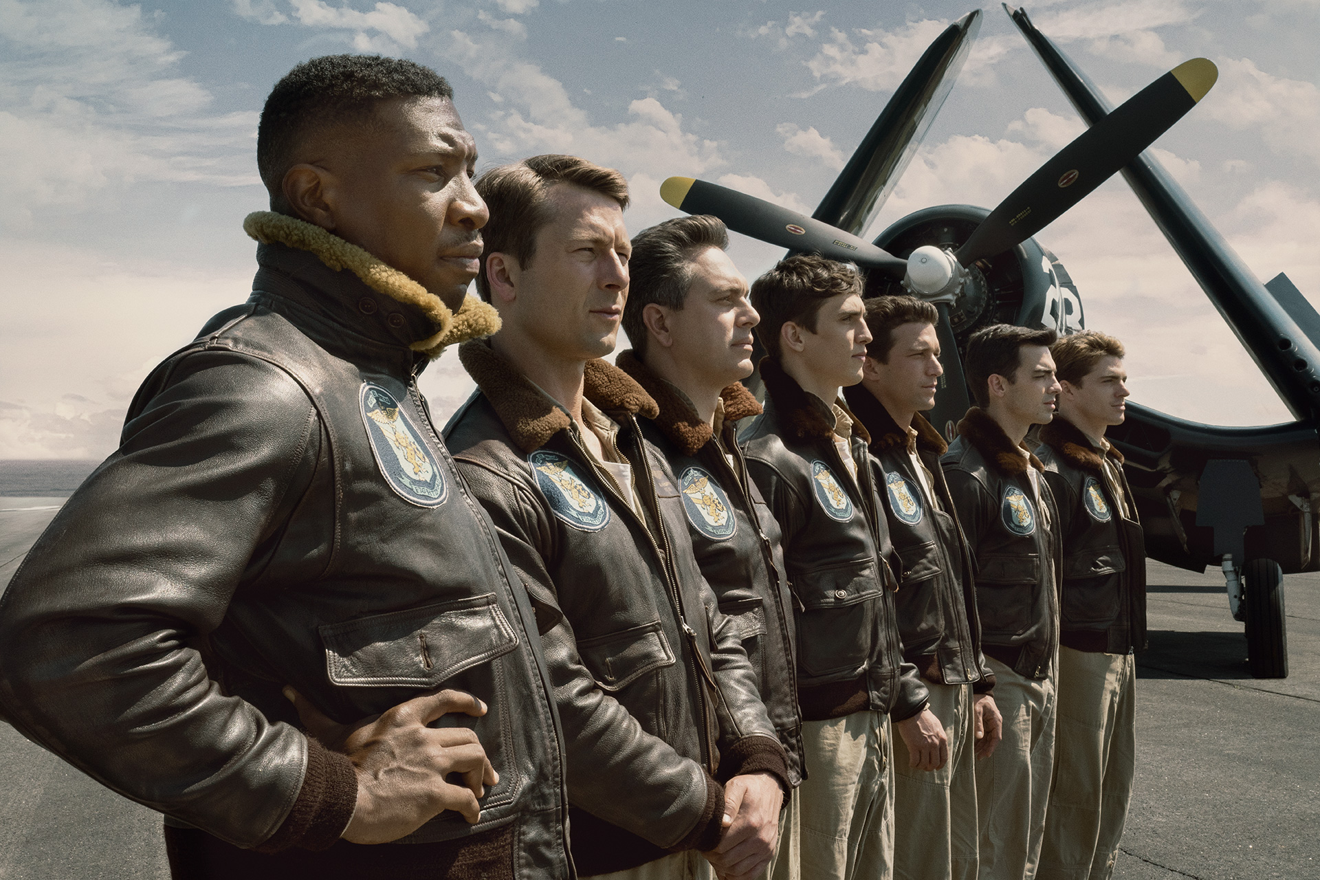 Film still for DEVOTION featuring Jesse Brown (Jonathan Majors), Tom Hudner (Glen Powell), Dick Cevoli (Thomas Sadoski), Carol Mohring (Nick Hargrove), Bill Koenig (Daren Kagasoff), Marty Goode (Joe Jonas) and Bo Lavery (Spencer Neville) all lined up in front of a Corsair.