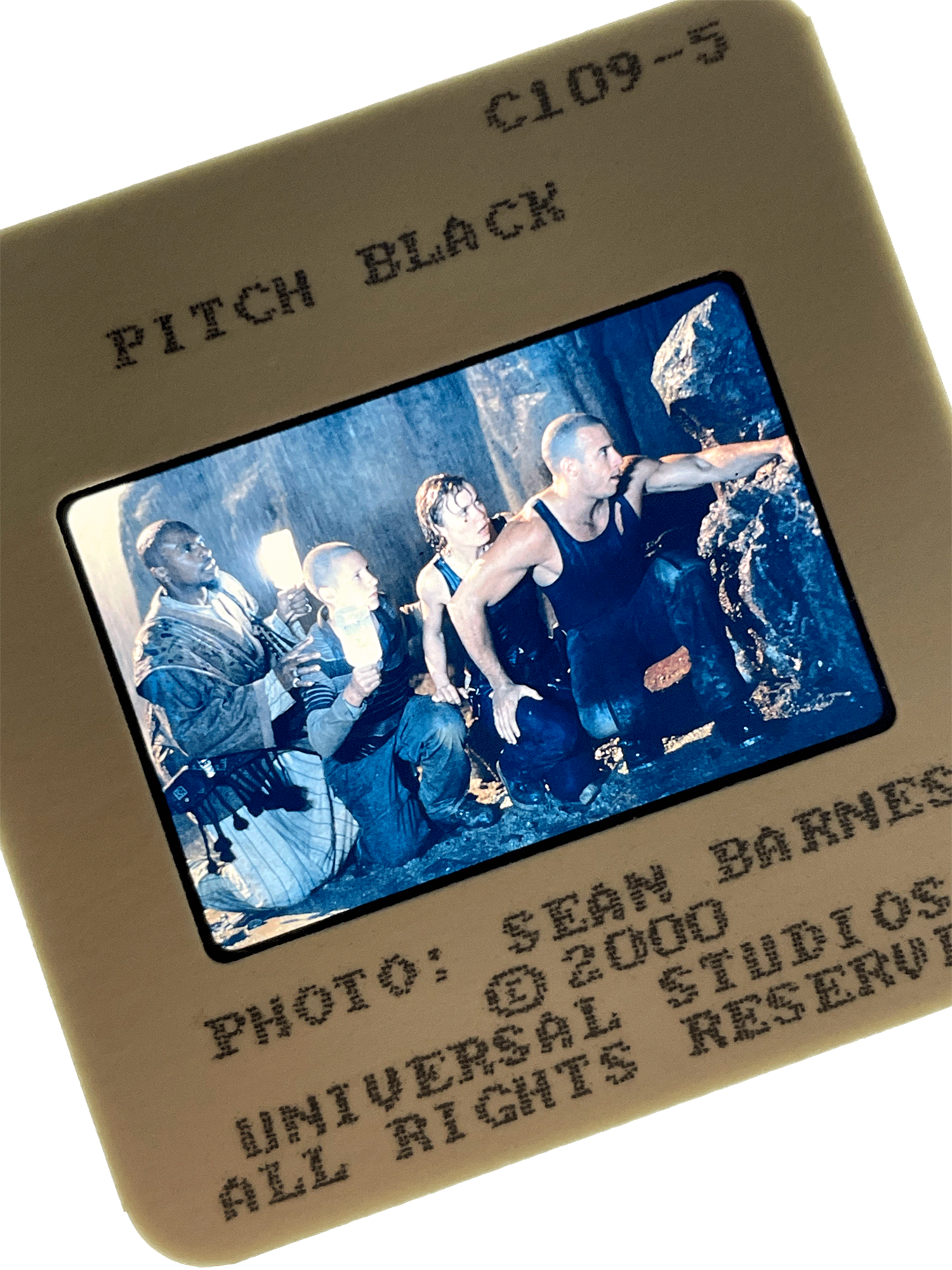 A slide from PITCH BLACK showing Vin Diesel, Radha Mitchell, and others crouching in the dark. Photo by Sean Barnes.