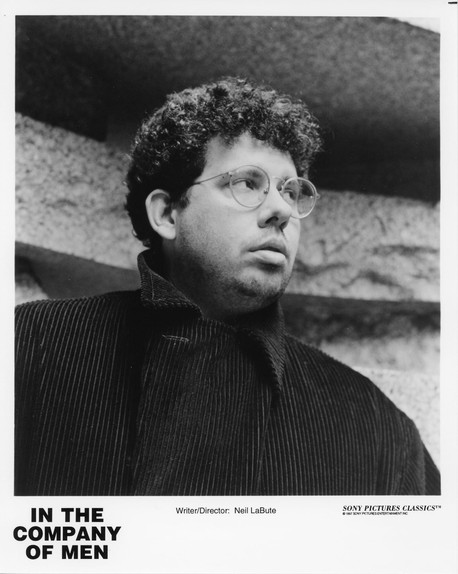 Portrait of a man outside in a heavy coat and wearing glasses, looking off-screen.