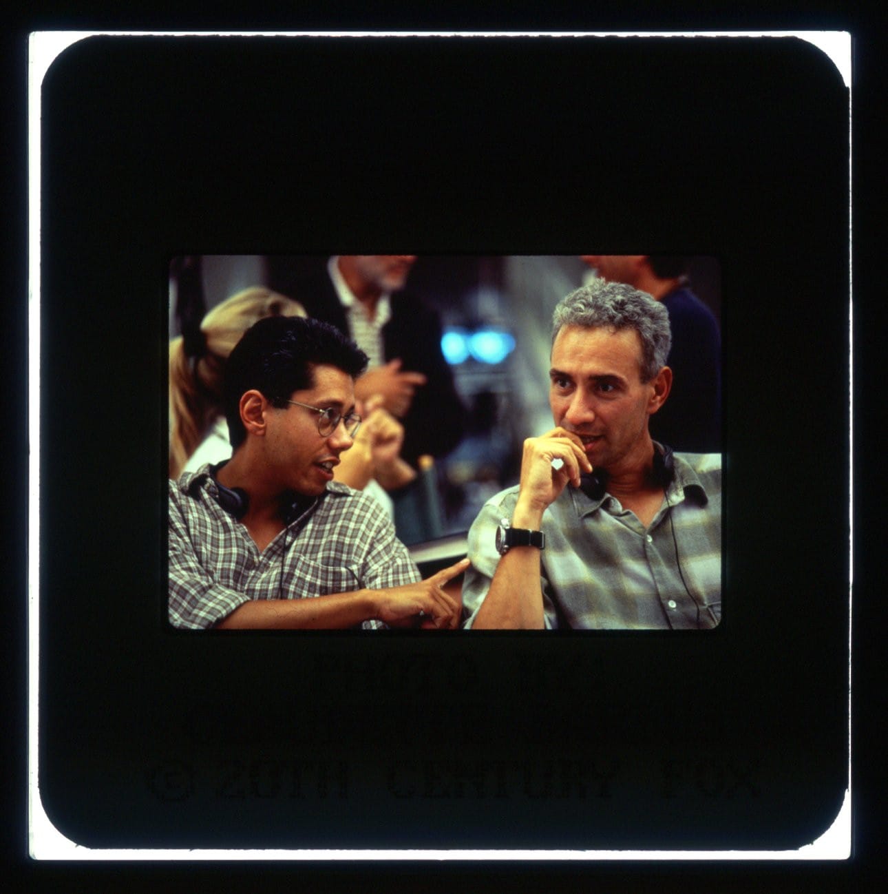 Shown sitting next to each other, Devlin pointing and talking while Emmerich listens with hand to mouth