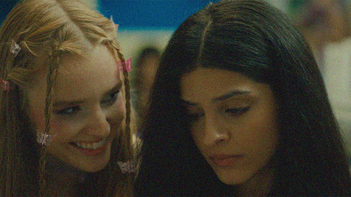 A white teen grins sinisterly as a forlorn-looking Persian teen in close-up.