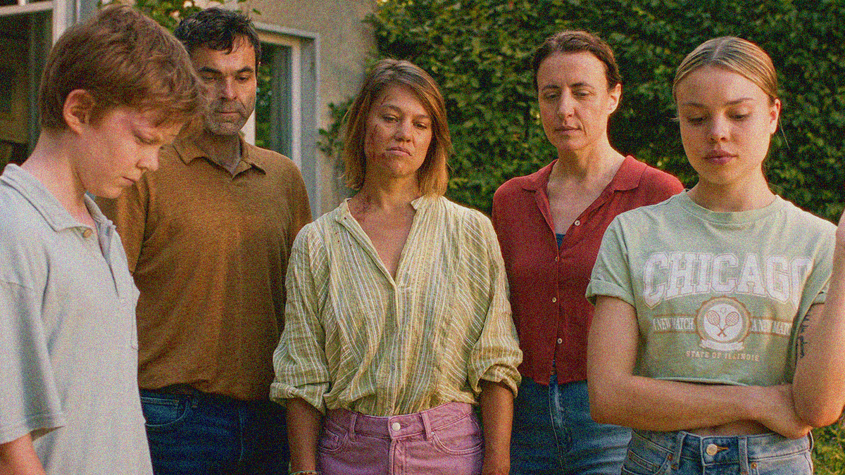 A group of people blocked side by side are all staring down and frowning at the ground.