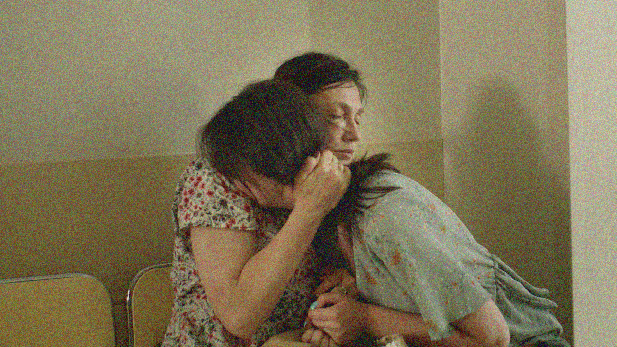 A woman holds another in an embrace as the latter cries.