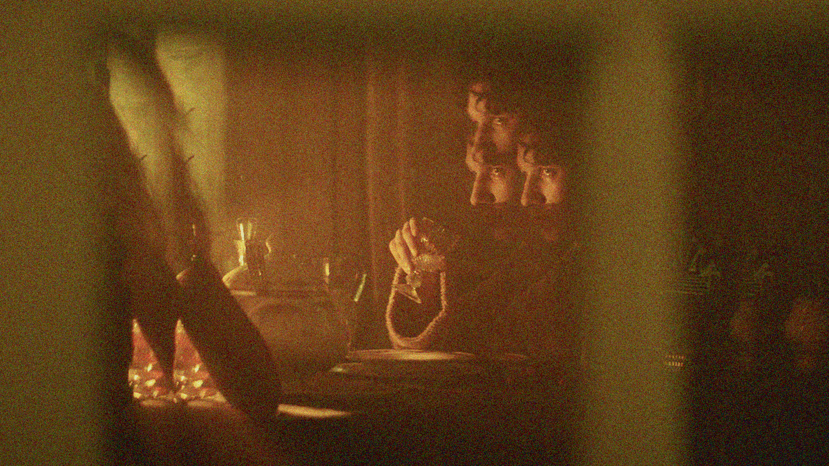 A man sitting at a table with a glass chalice in his hand is distorted and refracted by mirror to duplicate and triplicate certain aspects.