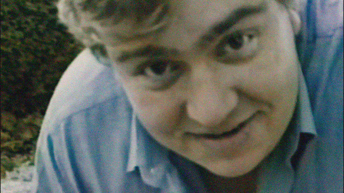 Extreme close-up of John Candy leaning over and smiling into the camera.