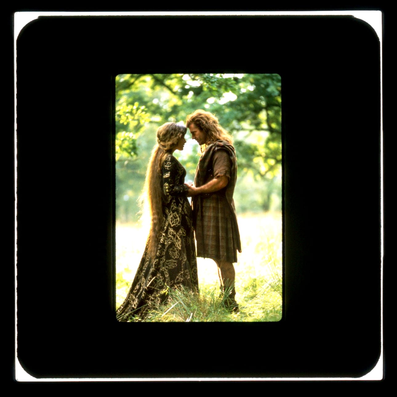Full length vertical shot of a woman and man standing face to face, hands in hand, foreheads almost touching.