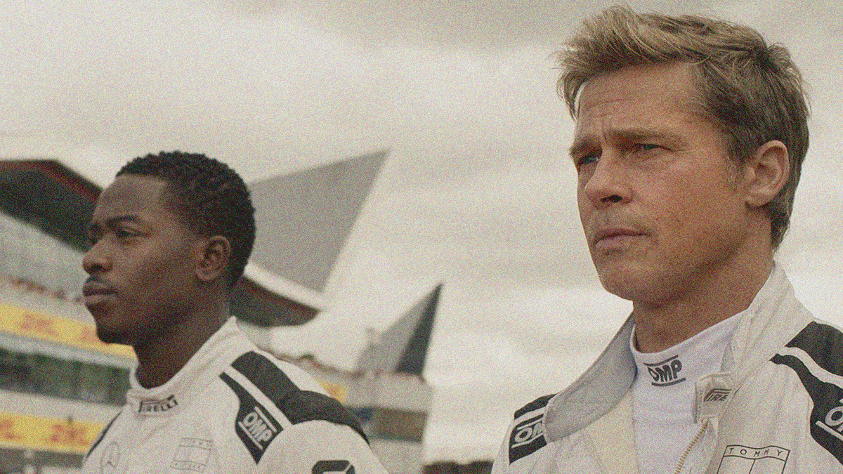 Close-up of two men standing in racing jackets and looking off-screen to the left.