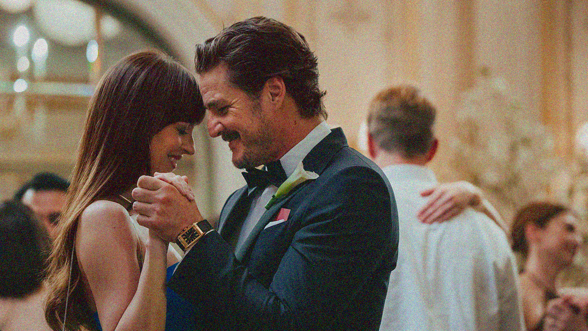 A woman and man dance at a wedding, both heads bowed with big smiles.