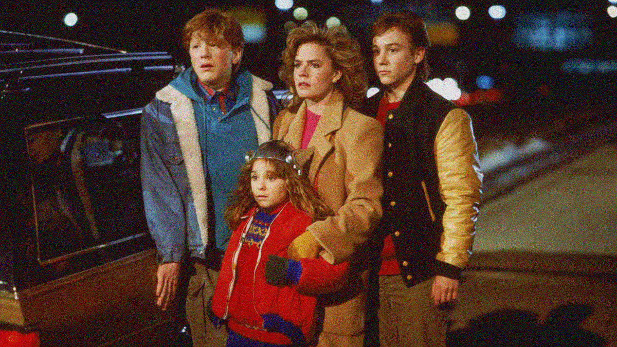 Three teens (boy in jean jacket, girl in beige jacket, boy in letterman jacket) and a young girl (in red jacket with silver Thor helmet) look off-screen left in fear while standing on the shoulder of an expressway.
