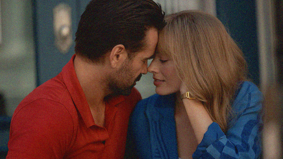 Close-up of a man in red and woman in blue romantically touch foreheads while sitting outside a front door.