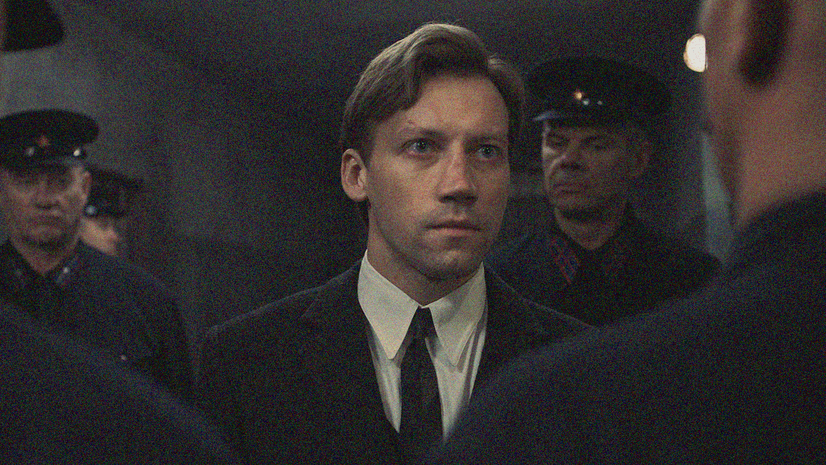 A man stared determinedly at a man blocking his way in the foreground while two men block his way in the background too..